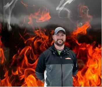 Casey, male crew chief smiling and standing against fake fire backdrop