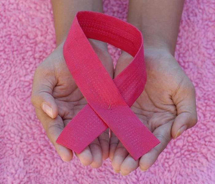 Hands holding pink breast cancer ribbon 